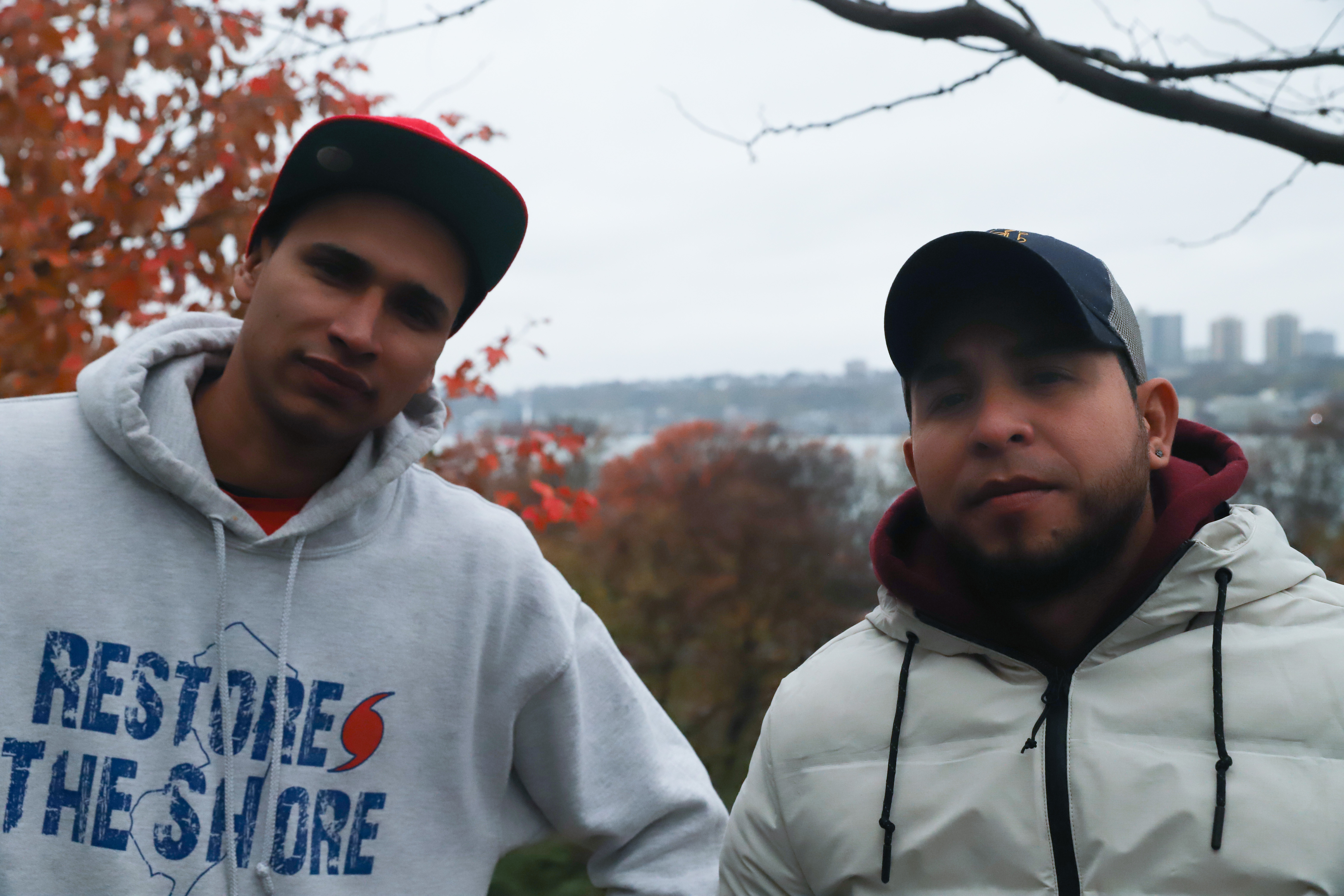 Two men in baseball caps stand in Riverside Park, New York City